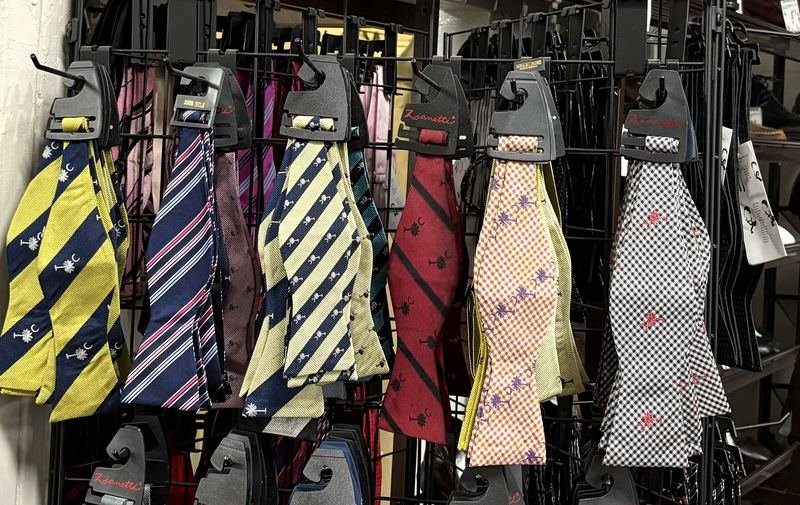 A rack of self-tie bow ties — South Carolina palmetto-and-crescent, Gamecock garnet, stripes and gingham checks.